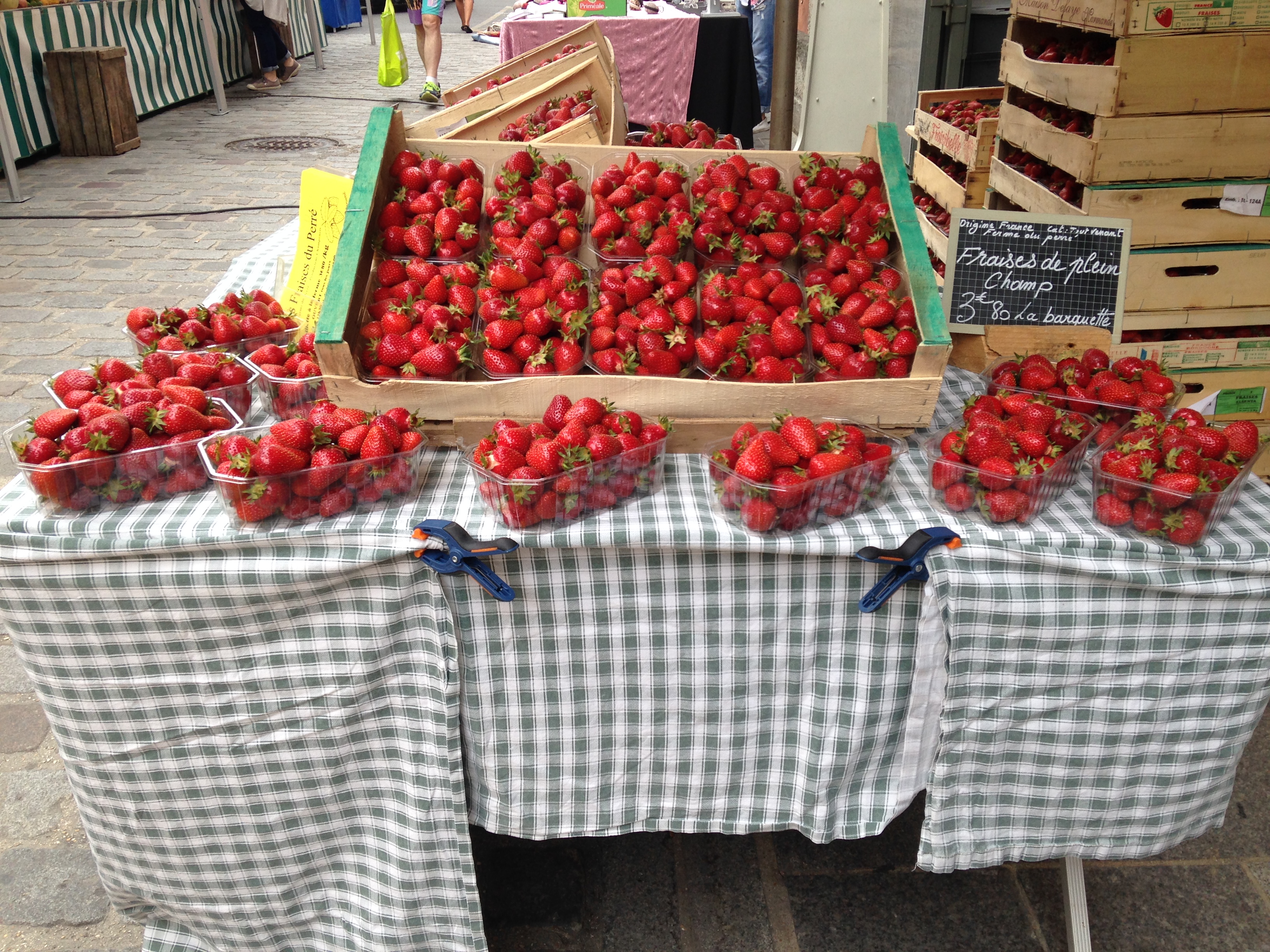Étal de marché avec barquettes de fraises fraîches et cageots en bois